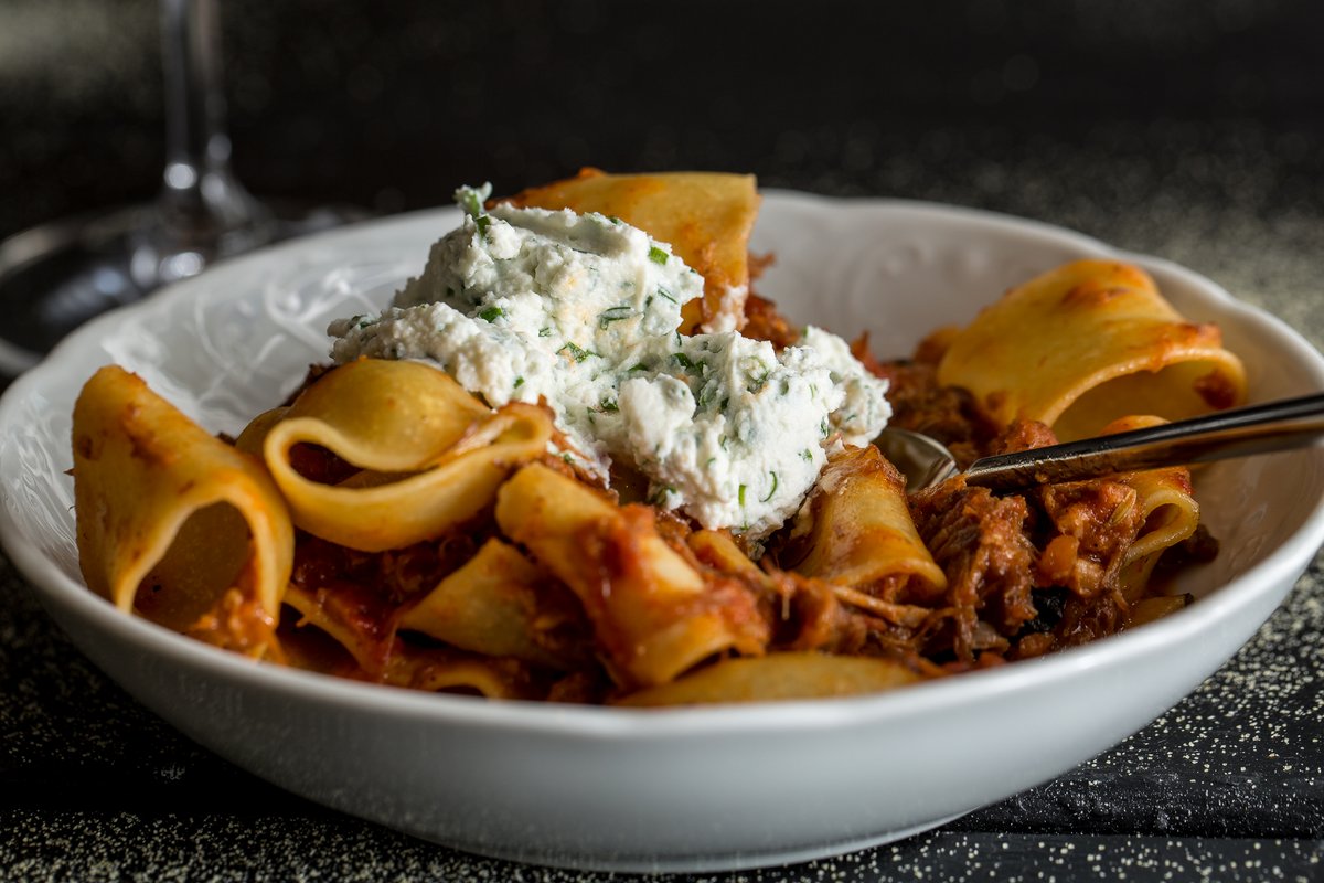 Homemade pasta with ricotta and meat sauce with spoon in white bowl
