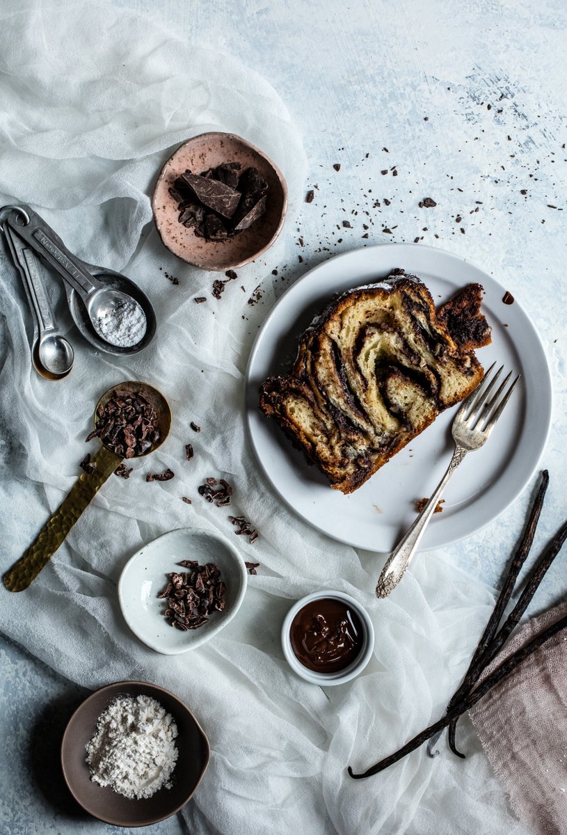 Bakery babka on white plate with vintage fork and chocolate pieces