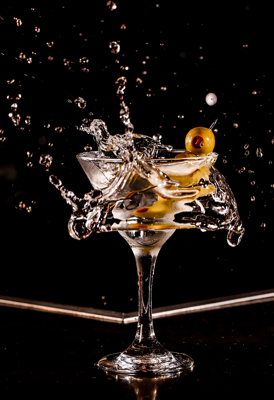 Olives being dropped into martini glass