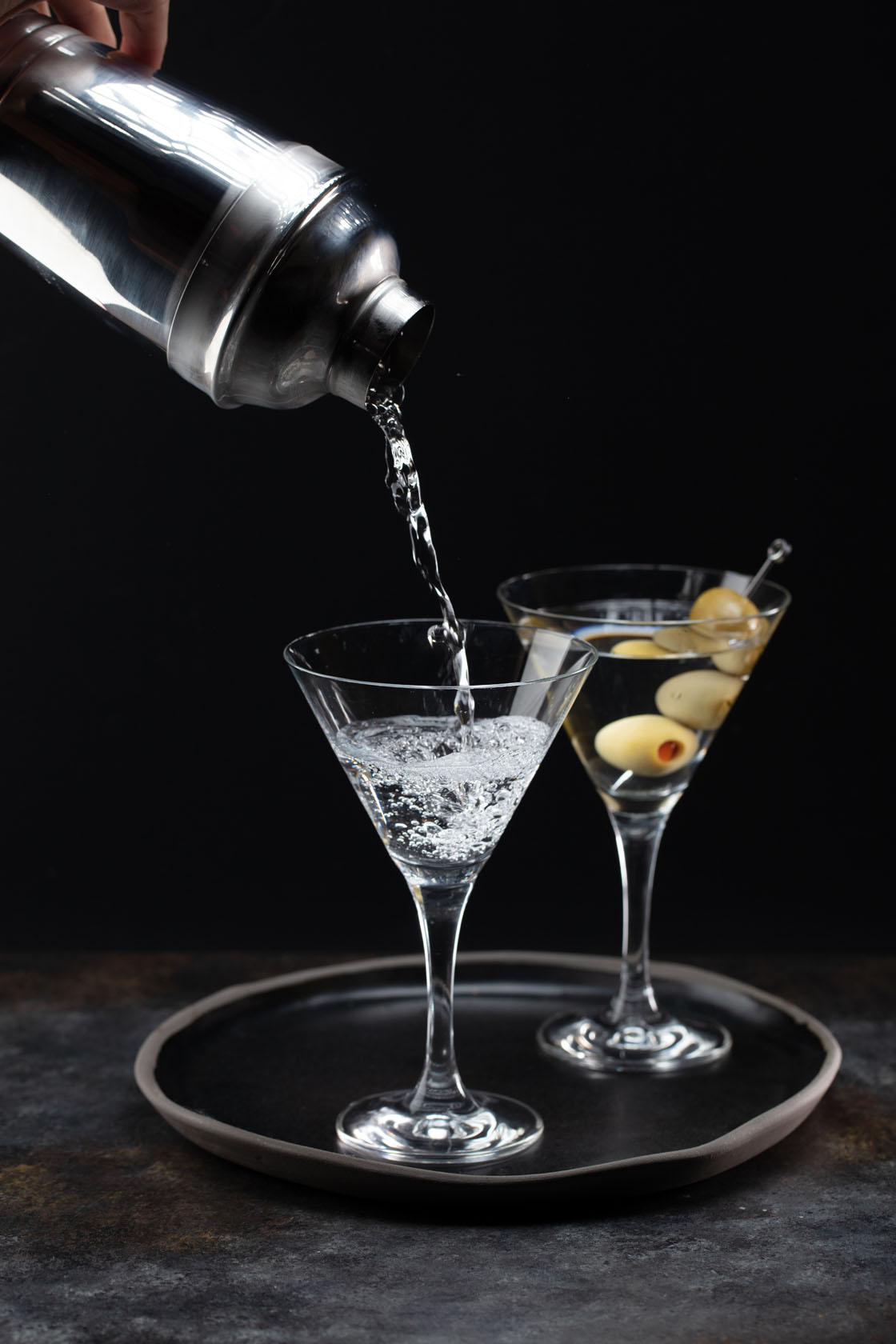 Martini being poured from shaker into two martini glasses
