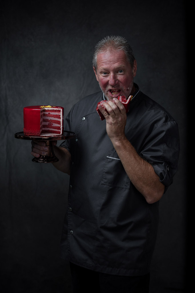 Creative portrait of chef eating a big slice of red velvet cake