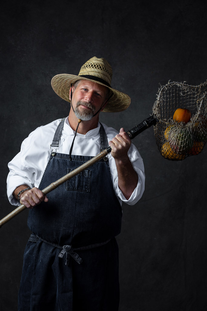 Chef in farmers hat and mango net holding mangos