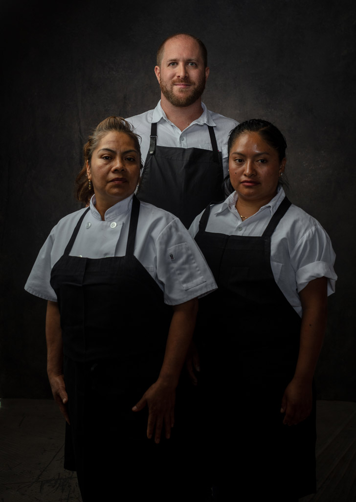 Moody photo of executive chef posing with his two women