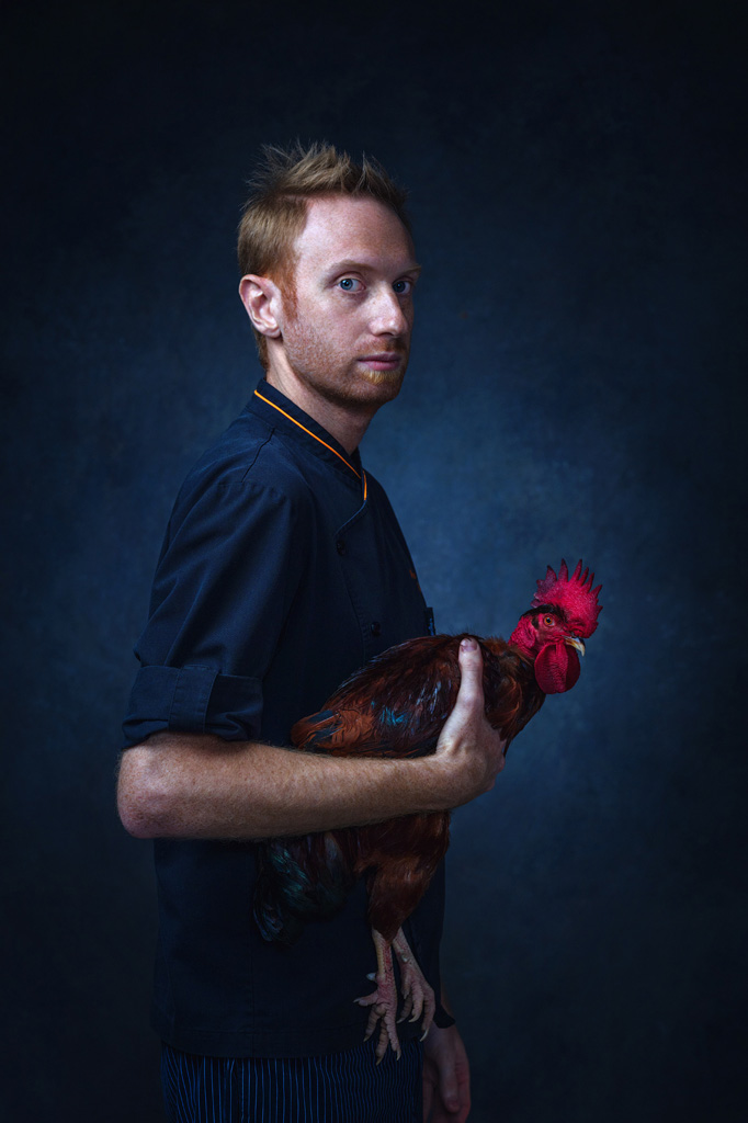 Stunning portrait of Italian chef holding a rooster in Vermeer Dutch lighting