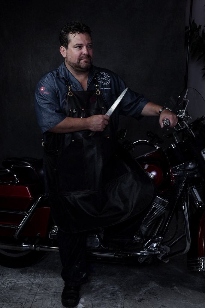 Dreamy portrait of chef on Harley motorcycle while holding sharp knife
