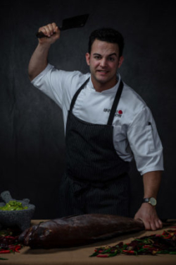 Portrait photo of south Florida chef about to strike a fish with a knife