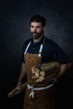 Creative portrait of beautiful chef holding firewood