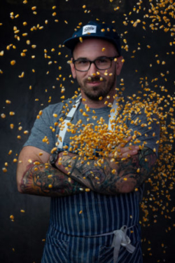 Smug chef posing in front of corn kernels falling around