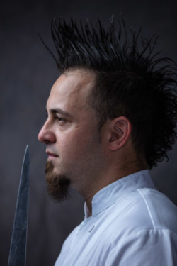 Chef with huge mohawk holding sharp chef knife