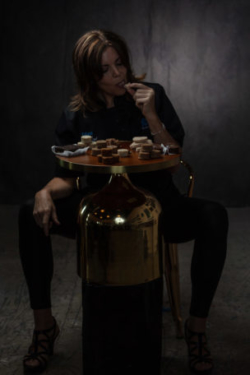 Creative, moody portrait of pastry artist sexily eating dessert