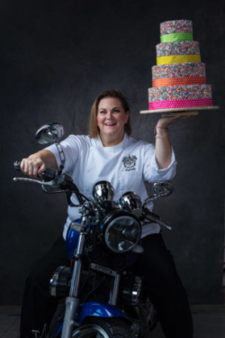 Beautiful photo of pastry artist on motorcycle holding large wedding cake