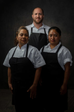 Moody photo of executive chef posing with his two women