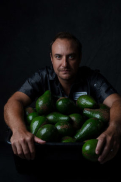 Intense photo of chef hugging a bowl full of avocados.
