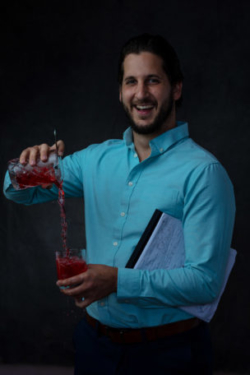 Happy mixologist pouring a negroni while holding a clipboard