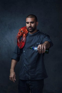 Beautiful portrait of chef pouring out a beer for his homies with a bright red lobster sitting on his shoulder