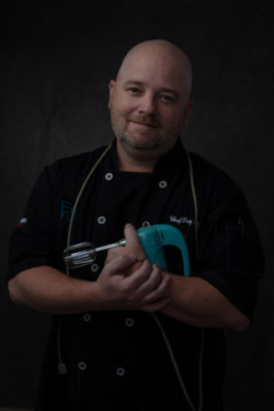 Photo of chef holding mixer to his chest lovingly
